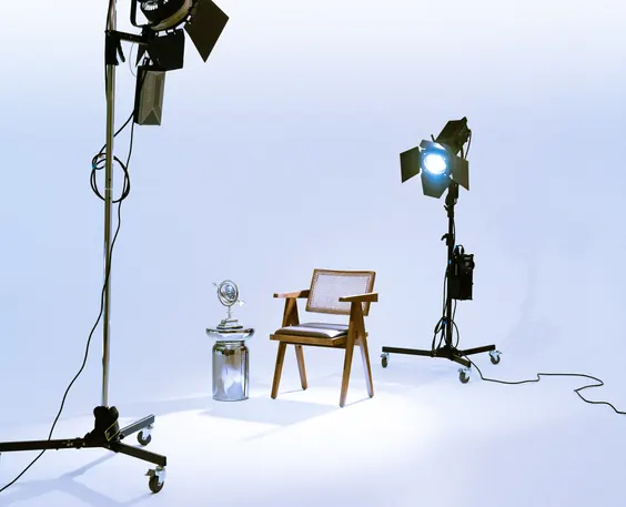 A studio set with two film lights aimed at a wooden chair on a white background