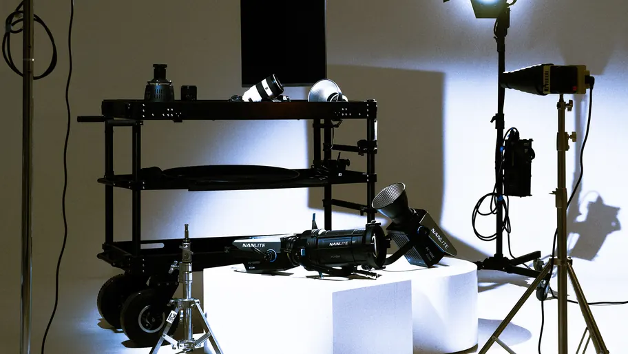 The madd. studio: a camera cart, lights on white blocks and a lamp on a stand, lit against a pale wall