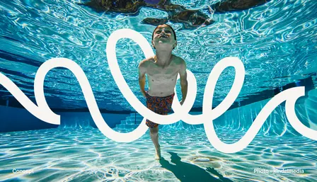 A boy swimming underwater towards the camera, the Valuri wave line drawn over the photo